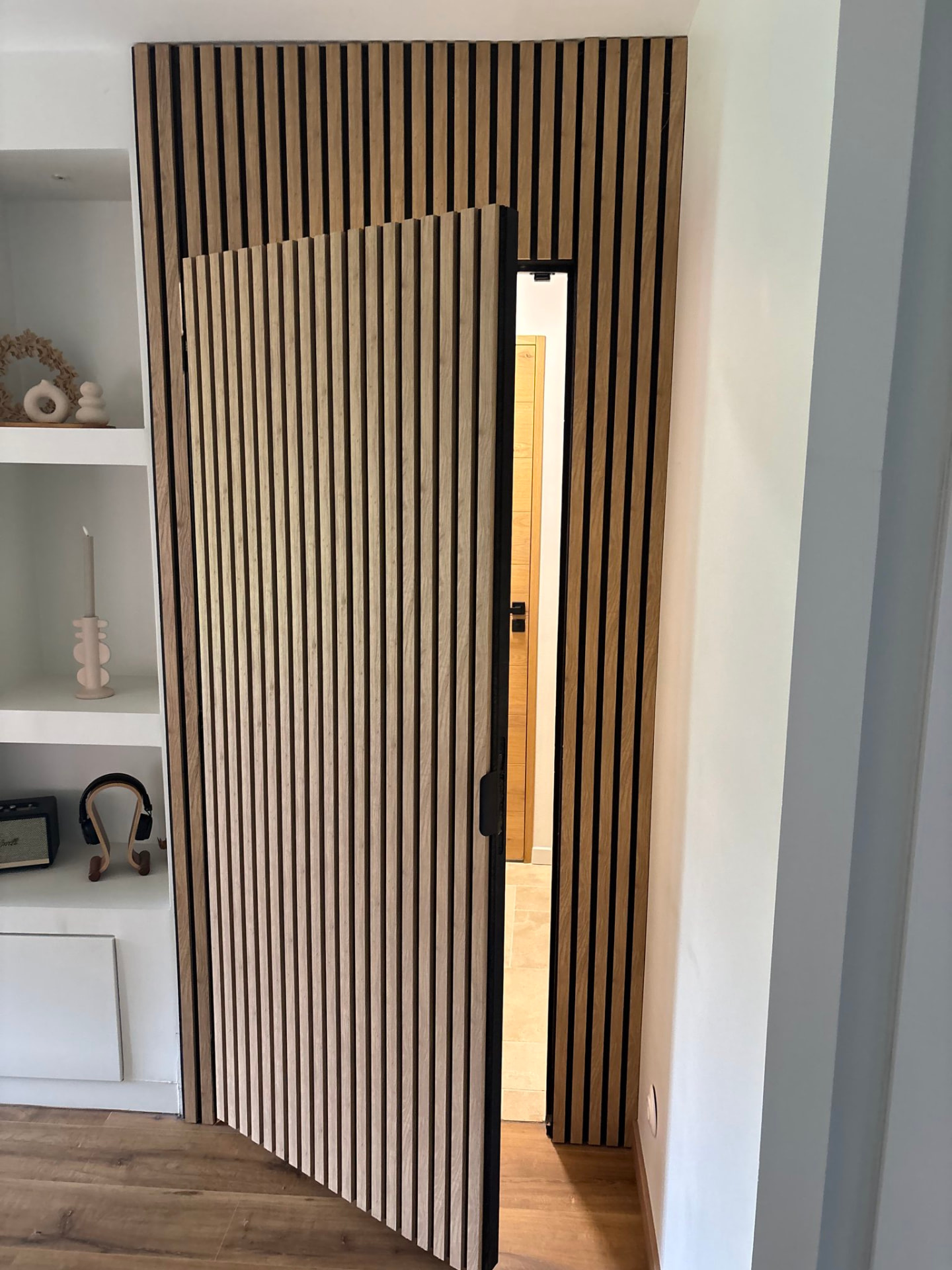 Porte invisible en tasseaux de bois ouverte sur le couloir