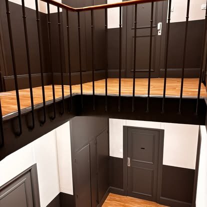 Cage d'escalier d'immeuble avec escalier noir et main courante en bois clair, Ressons-sur-Matz